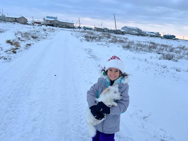 Daughter Willow holding a dog in snowy Newtok, Alaska