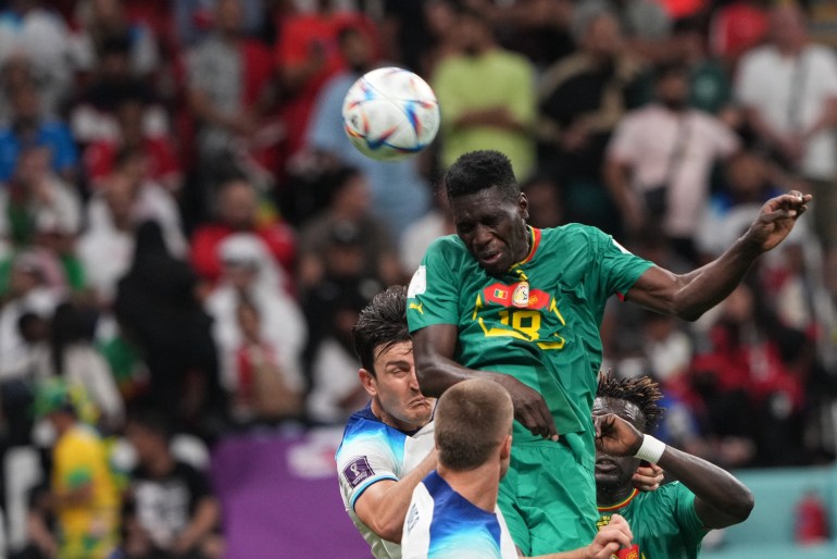 A Senegal jumps up towards the ball for a header as he is tackled by two England players.