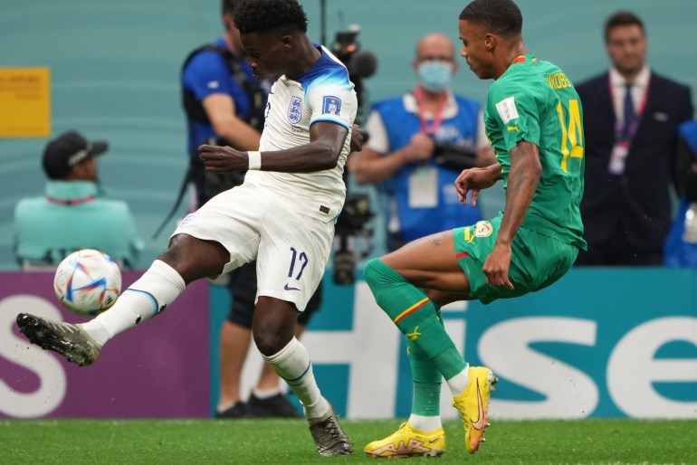 England's Bukayo Saka kicks the ball while Senegal's Ismail Jakobs looks to defend him.