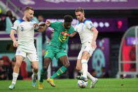 Senegal's Boulaye Dia being tackled by two English defenders.