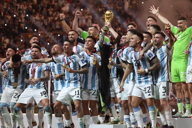 Lionel Messi lifts the World Cup trophy as Argentina players celebrate their triumph.