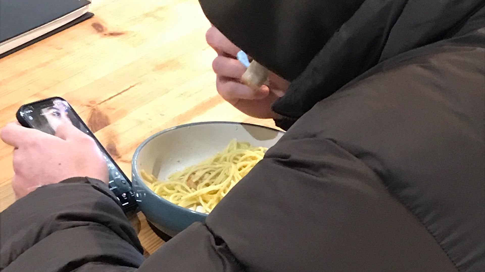 A person in a coat eating pasta