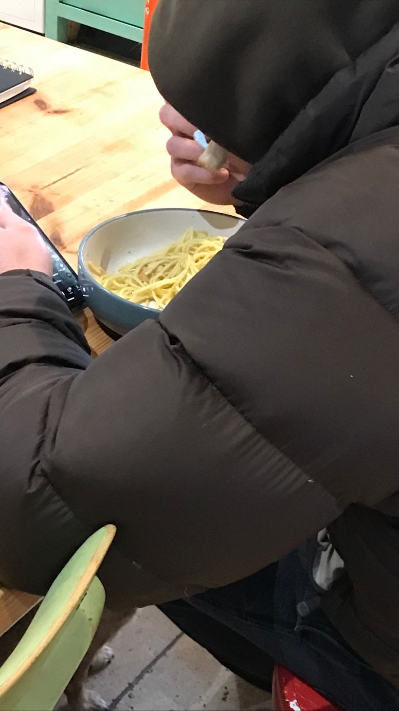 A person in a coat eating pasta