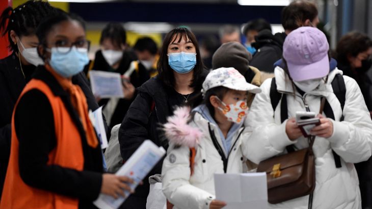 Passengers of a flight from China wait in a line for checking their COVID-19 vaccination documents as a preventive measure against the Covid-19 coronavirus, after arriving at the Paris-Charles-de-Gaulle airport in Roissy, outside Paris