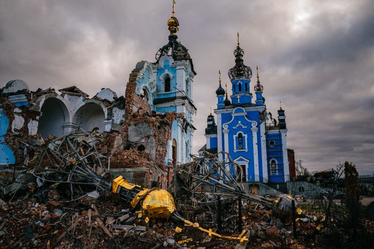 Construction workers climb onto the roof of a destroyed church in the village of Bohorodychne, Donetsk region