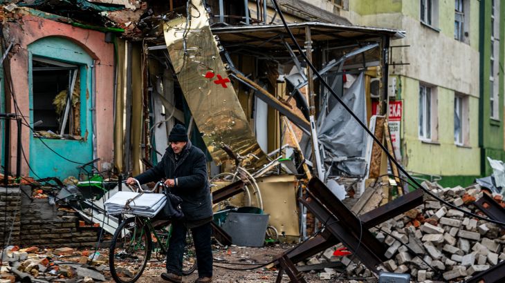 A local resident pushes his bicycle past "hedgehog" tank traps and rubble, down a street in Bakhmut, Donetsk region, on January 6, 2023, amid the Russian invasion of Ukraine. - Russia and Ukraine have both suffered heavy casualties in the fight for Bakhmut, and most of the city's pre-war population of 70,000 have left for safer territory, leaving behind cratered roads and buildings reduced to rubble and twisted metal. (Photo by Dimitar DILKOFF / AFP)