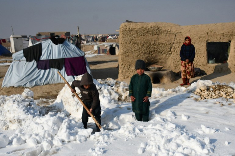 Afghan internally-displaced children shovel snow near their tents during a cold winter day at Nahr-e Shah-e- district of Balkh Province