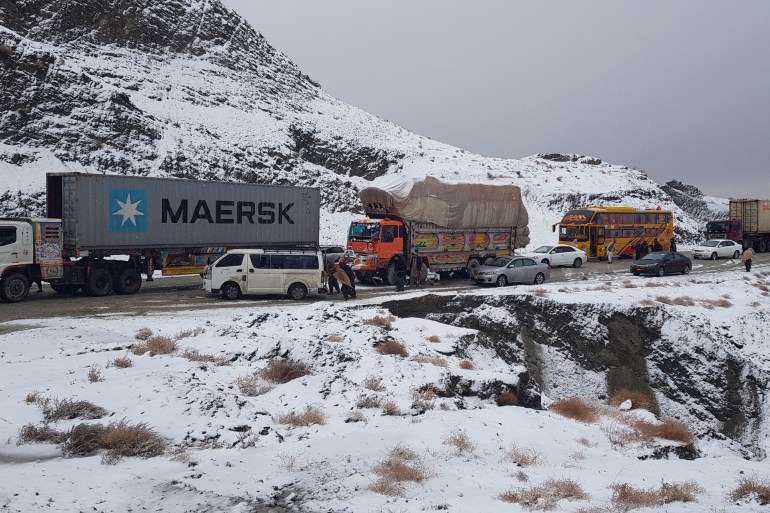 Vehicles are seen stuck along a road during a snowfall near the Pakistan-Afghanistan border in Chaman on January 18, 2023. (Photo by Abdul BASIT / AFP)