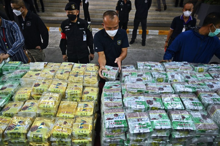 Thai policemen display packages of crystal methamphetamine before a press conference at the Narcotics Suppression Bureau in Bangkok on January 24, 2023. - More than a tonne of crystal meth was seized in less than a week, Thai police said Tuesday, after officers discovered some illicit stimulants hidden in tea and coffee bags. (Photo by Lillian SUWANRUMPHA / AFP)