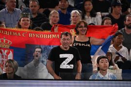 A man wearing a "Z" T-shirt watches the men's singles quarter-final match between Serbia's Novak Djokovic and Russia's Andrey Ruble on day ten of the Australian Open tennis tournament in Melbourne on January 25, 2023.