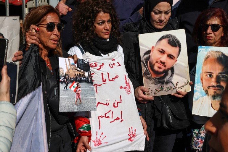 Relatives of victims of the 2020 Beirut port explosion, hold posters bearing images of people killed in the blast, during a rally outside the palace of justice in the Lebanese capital, to support the judge investigating the disaster, on January 26, 2023, after he was charged by the country's top prosecutor in the highly political case. - One of history's biggest non-nuclear explosions, the August 4, 2020 blast destroyed much of the Lebanese capital's port and surrounding areas, killing more than 215 people and injuring over 6,500. No official has been held accountable for the disaster. (Photo by Joseph EID / AFP)