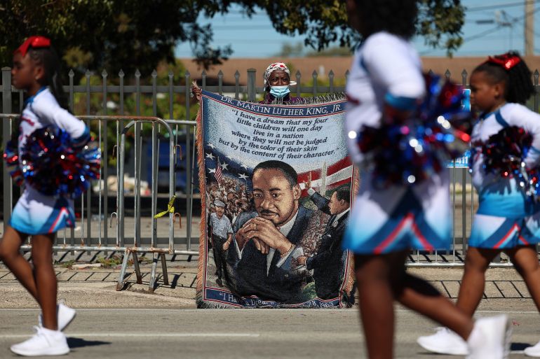 Diane McDonald holds a banner during the Dr. Martin Luther King Jr. Day Parade as it makes its way past in the Liberty City neighborhood on January 16, 2023 in Miami, Florida. The annual event honors the late civil rights leader. Joe Raedle/Getty Images/AFP (Photo by JOE RAEDLE / GETTY IMAGES NORTH AMERICA / Getty Images via AFP)