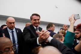 Jair Bolsonaro shakes a hand in a crowded room in Miami