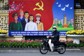 A man rides past a poster of the 13th National Congress of the Communist Party of Vietnam in Hanoi, Vietnam, in January 25, 2021 [File: Thanh Hue/Reuters]