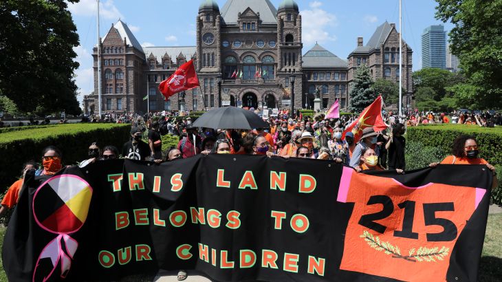 Protesters hold a banner during a march from the Ontario provincial legislature, after the remains of 215 children were found on the grounds of the Kamloops Indian Residential School, in Toronto, Ontario, Canada June 6, 2021. REUTERS/Chris Helgren