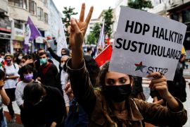 A demonstrator makes a v sign and holds a banner reads "HDP is people, they can't be silenced" during a protest in solidarity with pro-Kurdish Peoples' Democratic Party (HDP)