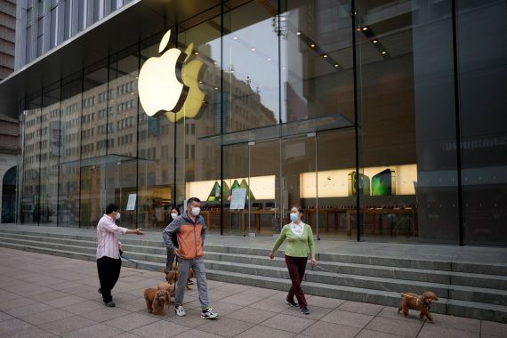 People wearing face masks walk their dogs past an Apple store on a shopping street, after the lockdown placed to curb the coronavirus disease (COVID-19) outbreak was lifted in Shanghai, China June 1, 2022. REUTERS/Aly Song