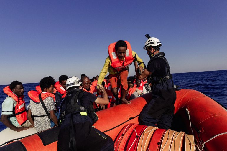 A Sea-Watch crew member helps a migrant boarding a dinghy in the Mediterranean Sea. [File photo: Reuters]