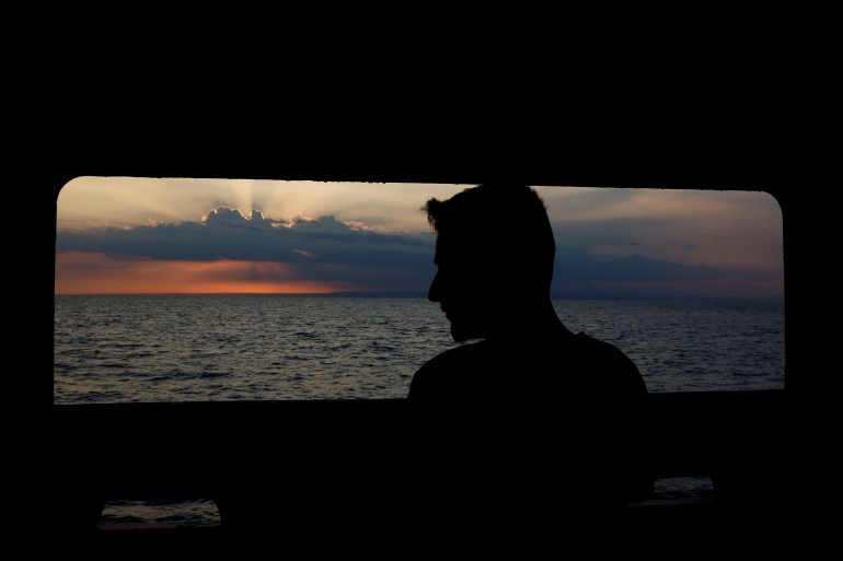A refugee looks at the sunshine over Sicily island from a rescue boat