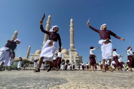 Yemeni men dance with traditional daggers in front of a mosque in Sanaa