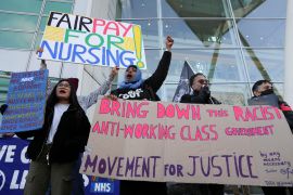 People hold signs outside University College Hospital as NHS nurses march during a strike, amid a dispute with the government over pay, in London
