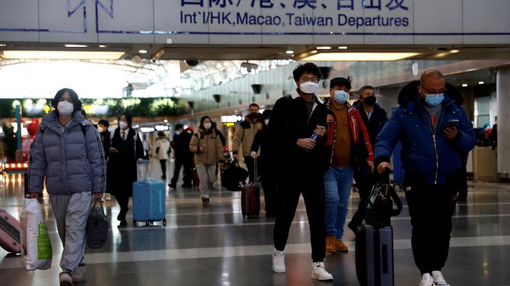 Travellers walk with their luggage at Beijing Capital International Airport