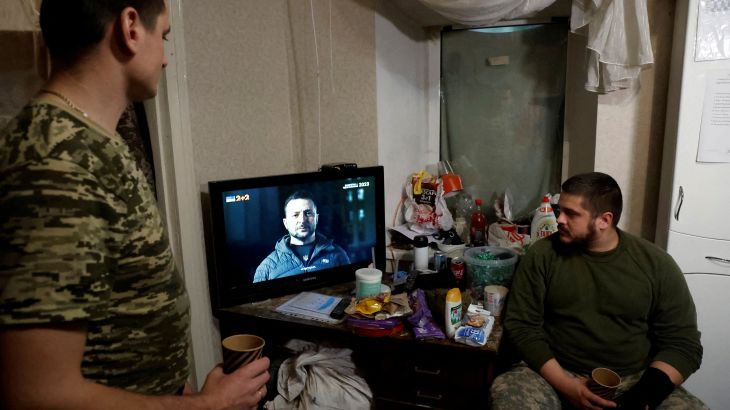Ukrainian soldiers watch Ukraine's President Volodymyr Zelenskiy’s New Years Eve address to the nation