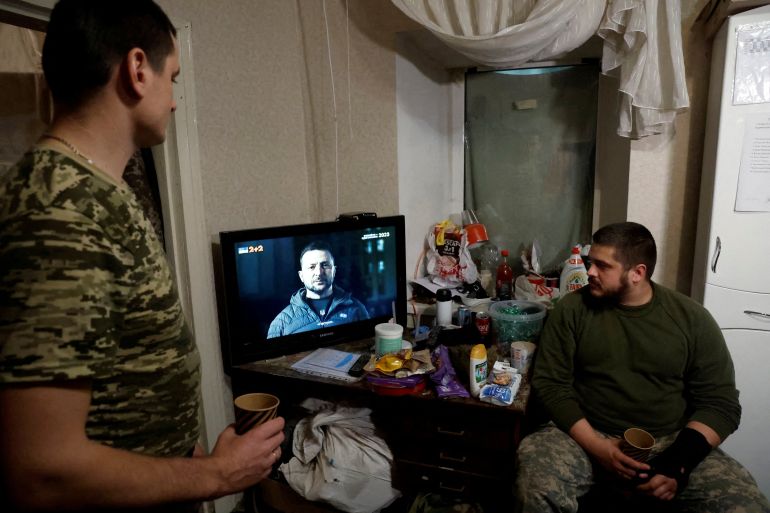 Ukrainian soldiers watch Ukraine's President Volodymyr Zelenskiy’s New Years Eve address to the nation