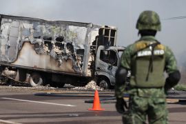 A soldier keeps watch near a burnt out truck in Sinaloa state, Mexico