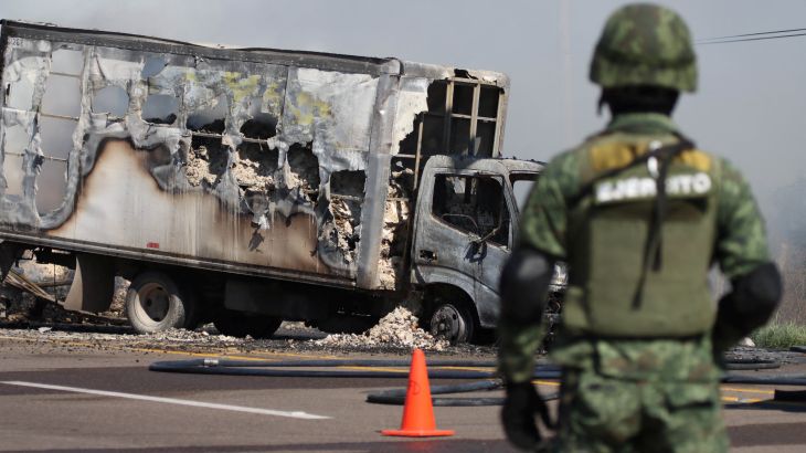 A soldier keeps watch near a burnt out truck in Sinaloa state, Mexico