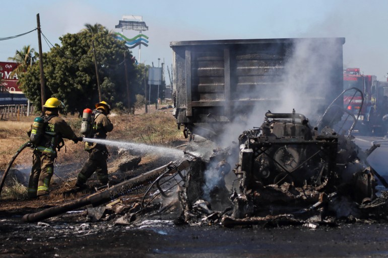 Firefighters extinguish a fire of a vehicle after violence in Mexico