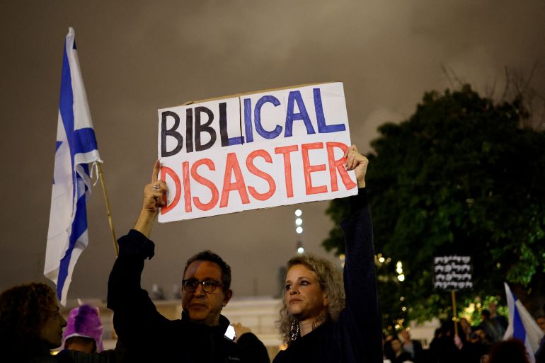 Protesters hold up a sign that reads 'Biblical Disaster' as they demonstrate against the right-wing government led by Prime Minister Benjamin Netanyahu in Tel Aviv, Israel.
