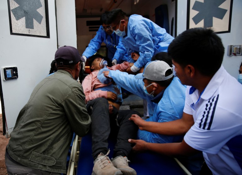 An injured man being loaded into an ambulance by protesters and healthcare workers