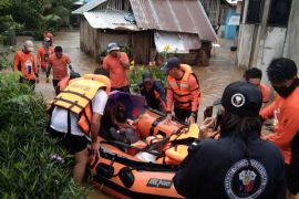 Members of the Philippine Coast Guard assist residents affected by floods during a rescue operation, in Lamitan City