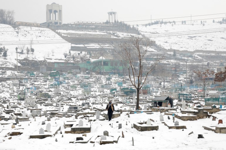 An Afghan man walks on a snow-covered cemetery in Kabul