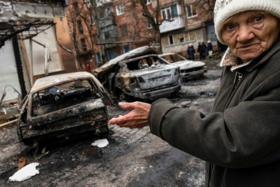A local resident gestures near burned cars destroyed by a Russian military strike in Kherson