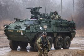 A US soldier standing in front of a Stryker armoured vehicle. It looks cold and damp. The picture was taken during joint exercises with South Korean forces in January