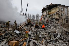Emergency personnel work among debris at the site where a building was heavily damaged in recent shelling in Donetsk, Russian-controlled Ukraine