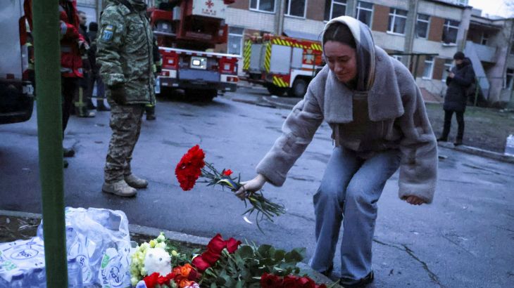 A woman lays flowers near the site of the helicopter crash in Brovary, Ukraine