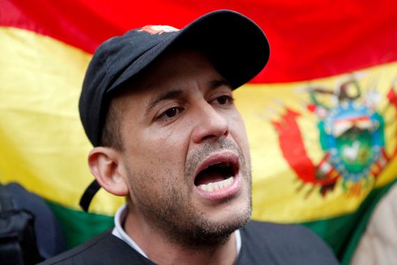 Luis Fernando Camacho speaks against the backdrop of a flag