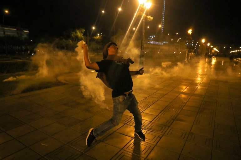 A protester throws a tear gas canister during the 'Take over Lima' march