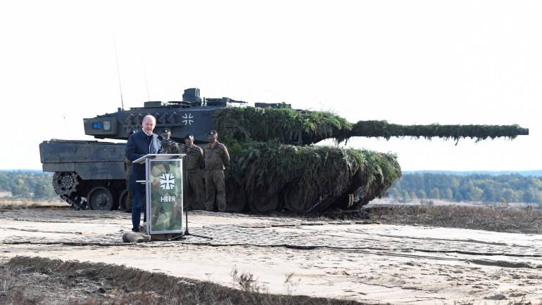 German Chancellor Olaf Scholz delivers a speech in front of a Leopard 2 tank 