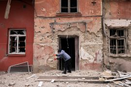 Zoya Mykolaivna, 84, removes debris in front of her apartment at a residential building damaged by a Russian military strike in Kherson, Ukraine January 25, 2023
