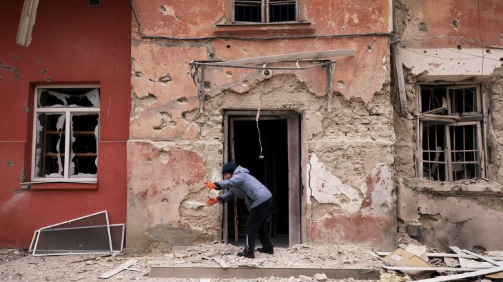 Zoya Mykolaivna, 84, removes debris in front of her apartment at a residential building damaged by a Russian military strike in Kherson, Ukraine January 25, 2023