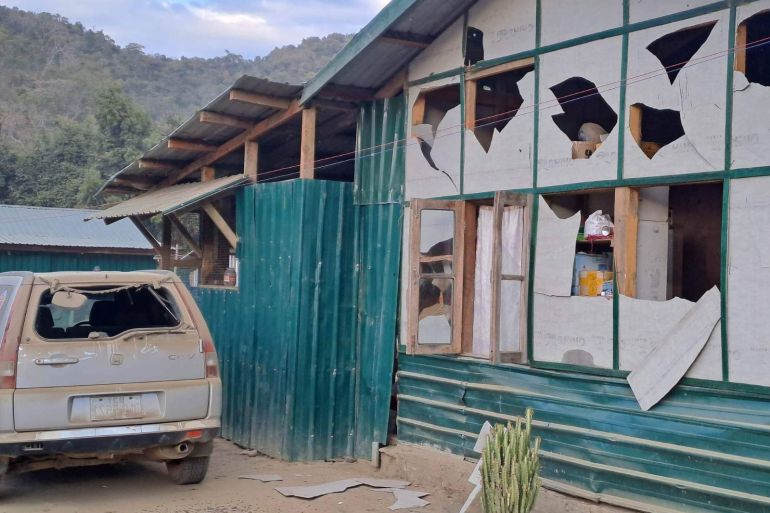 A house and car damaged by the Myanmar military attacks at Camp Victoria, The panels making up the wooden building have been broken leaving large holes. The glass in the car has been blown out
