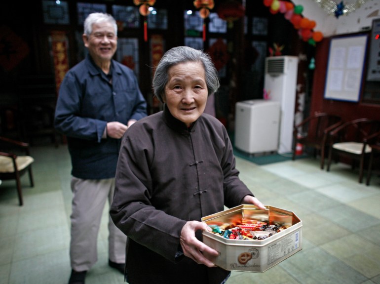 An elderly woman distributes goodies to visitors at the Fengyiyuan, a government-funded nursing home in downtown Beijing, Friday, March 19, 2010. China's current ratio of 16 elderly people per 100 workers is set to double by 2025, then double again to 61 by 2050, due partly to family planning policies that limit most families to a single child, a U.S. study said. (AP Photo/Andy Wong)