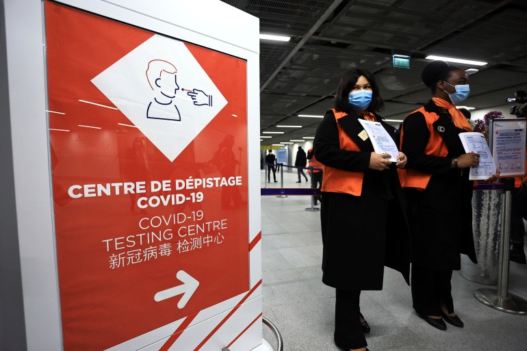 Airport staff wait from passengers coming from China in front of a COVID-19 testing area set at the Roissy Charles de Gaulle airport, north of Paris, Sunday, Jan. 1, 2023