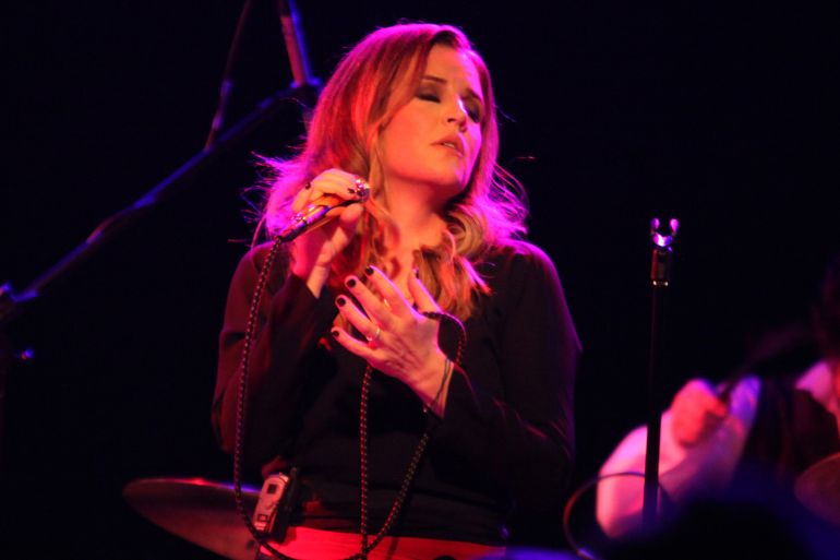 Lisa Marie Presley singing on stage, She has her eyes closed and looks lost in the music
