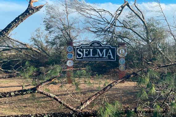Fallen trees surround a sign welcoming visitors to Selma, Alabama