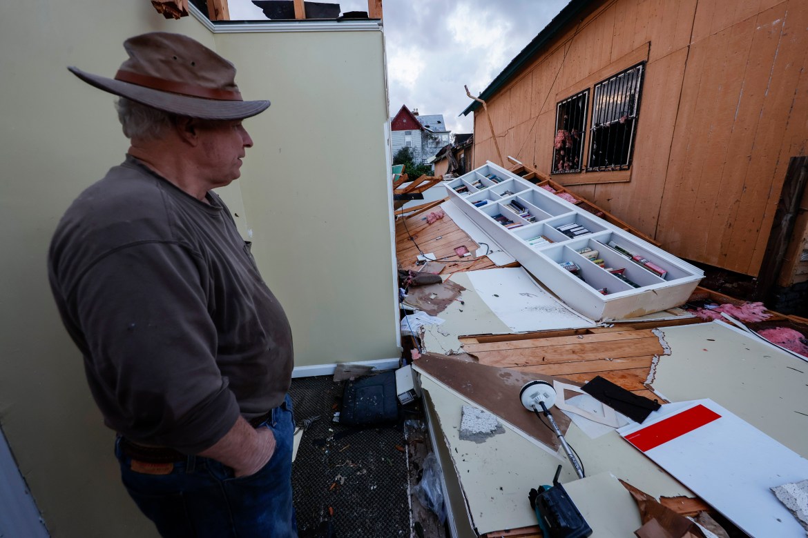A man surveys the damage inflicted to his house after Thursday's tornadoes